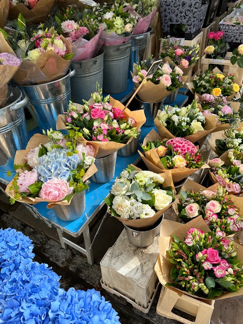 An array of freshly prepared floral bouquets displayed on a table, featuring a variety of pastel-colored flowers including pink roses, white lisianthus, and blue hydrangeas, all neatly wrapped in brow